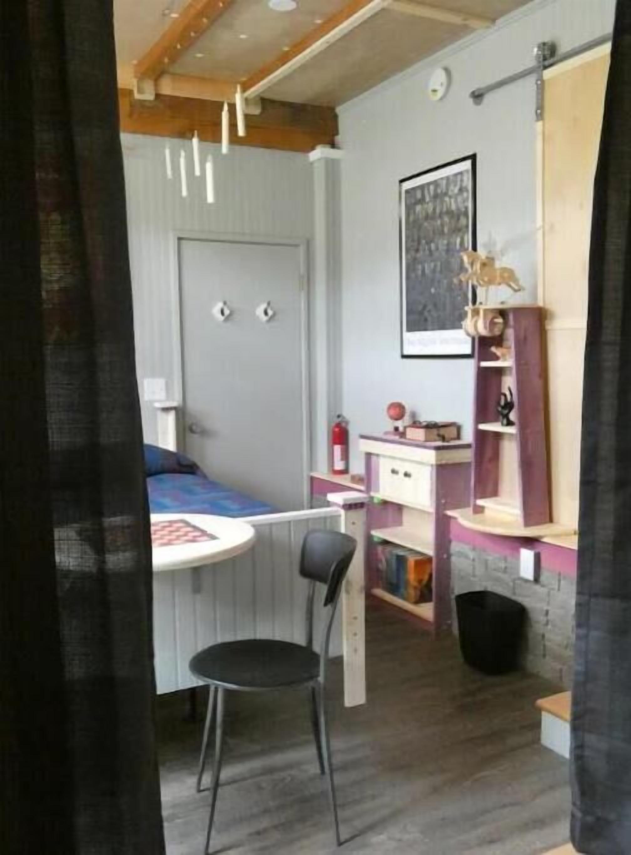 Ein gemütliches Schlafzimmer mit Bett, Schreibtisch und Stuhl. Es gibt eine Heizung, ein Bücherregal und ein gerahmtes Bild an der Wand.
