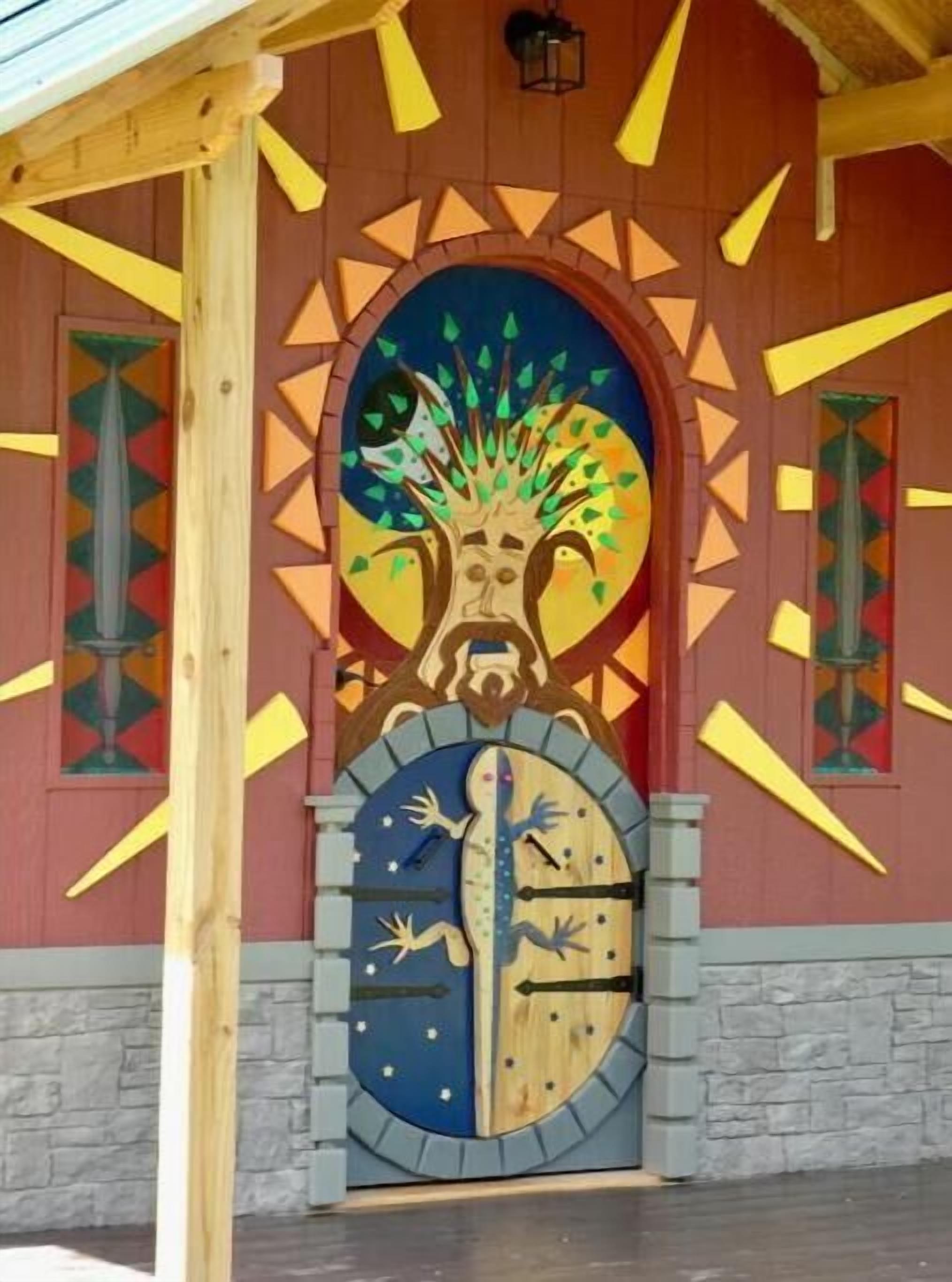 Entrada d'un edifici amb un mural colorit, un rellotge i una porta de fusta.
