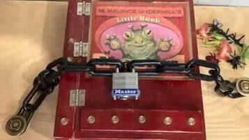 Ein rotes Buch mit dem Titel 'M. Maurice Underhills kleines Buch', das mit einer Kette versehen ist.
