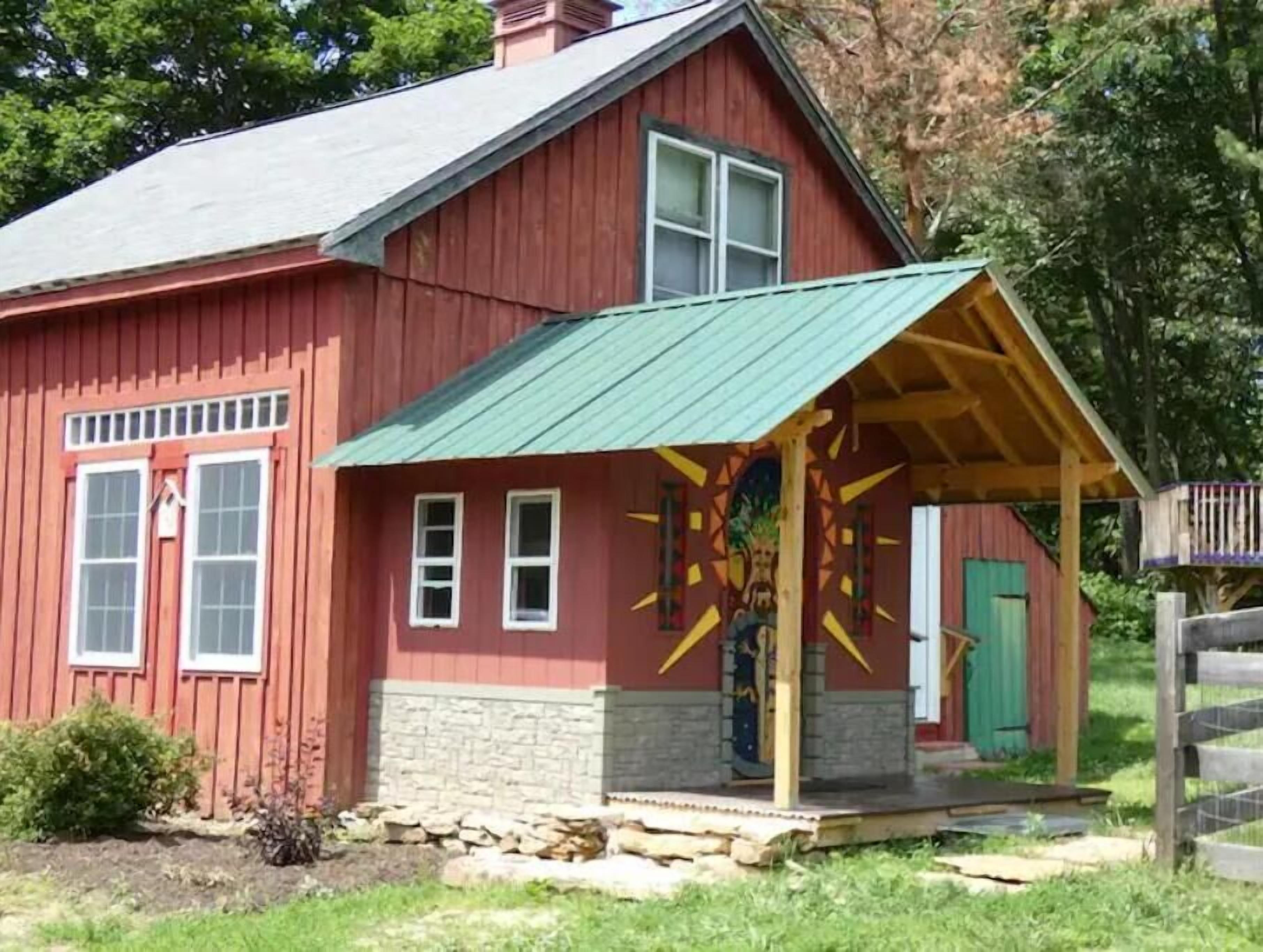 A red barn with a green roof and a colorful mural on the side.
