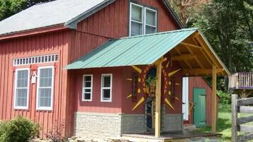 A red barn with a green roof and a colorful mural on the side.