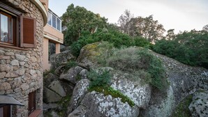 En bygning i sten med træpersienner og en balkon.