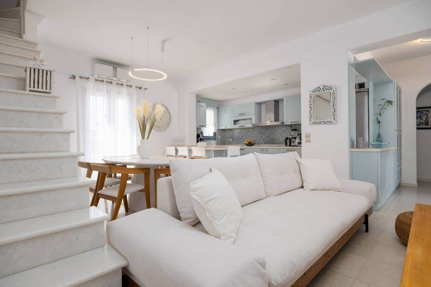 Ein modernes Interieur mit Treppe, Essbereich, Sofa und einer Küche im Hintergrund.