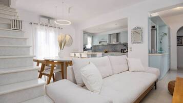 Ein modernes Interieur mit Treppe, Essbereich, Sofa und einer Küche im Hintergrund.