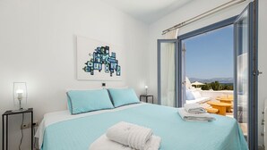 Quarto com cama, mesa de cabeceira, uma obra de arte na parede e vista para o exterior.