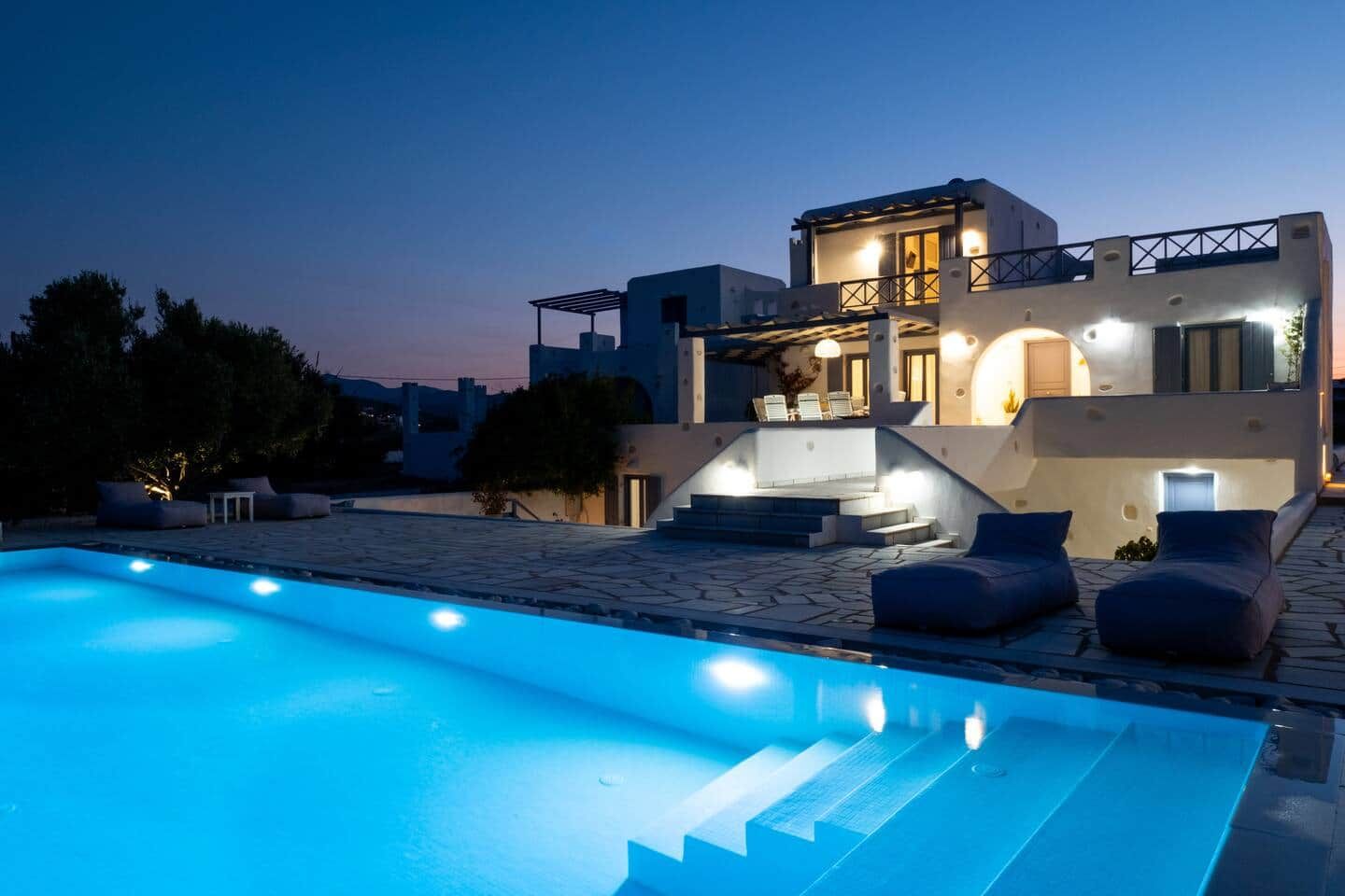 Ein modernes Haus mit Swimmingpool, Sitzgelegenheiten im Freien und einer Treppe zum Eingang.