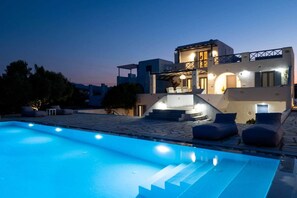 A modern house with a swimming pool, outdoor seating, and a staircase leading to the entrance.