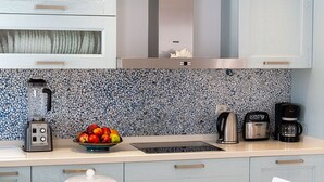 Uma cozinha moderna com painel de backsplash de pedra, chaleira, máquina de café e uma tigela de frutas.
