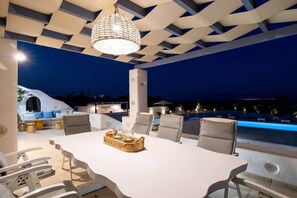 A rooftop terrace with a dining table, chairs, and a hanging light fixture.