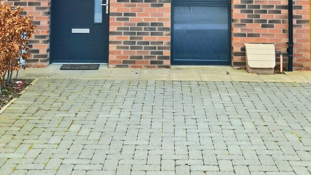 A two-story brick building with a black door and windows, a satellite dish, and a paved driveway. - Pennywell 2 Bedroom House - Edinburgh  (Edinburgh)