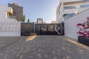 A gated driveway leading to a modern building with a stone facade and a garage door.