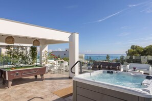 An outdoor pool area with a hot tub, a pool table, and lounge seating.