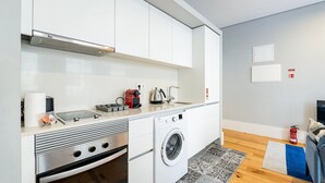 Une cuisine compacte équipée d’un four encastré, d’un lave-linge et d’un petit évier.