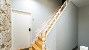 Un escalier avec des marches en bois et des balustrades blanches, menant à un palier avec une porte blanche.