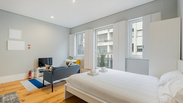 Une chambre à coucher moderne, équipée d’un lit, d’un bureau, d’une chaise et d’un téléviseur.