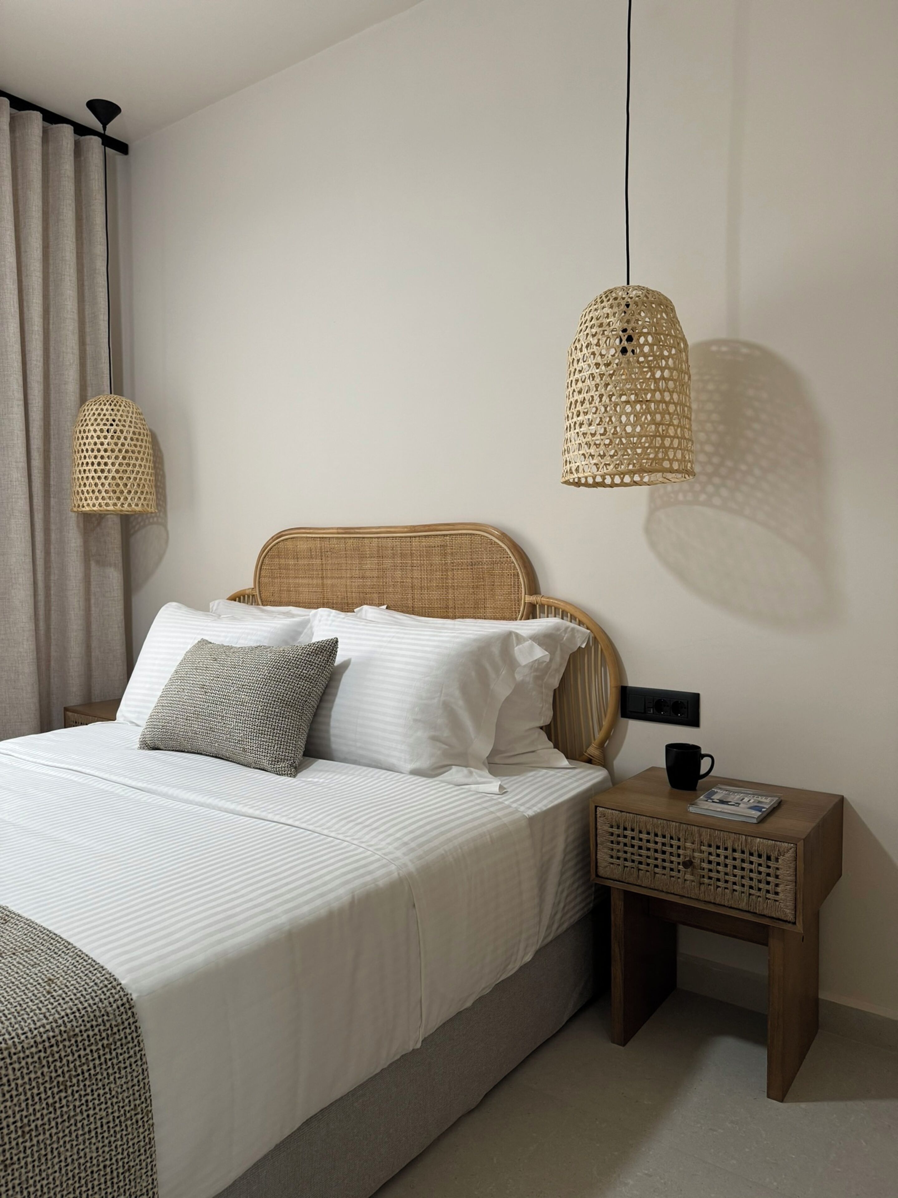 Ein ordentlich eingerichtetes Schlafzimmer mit Bett, Nachttisch und zwei Hängeleuchten.