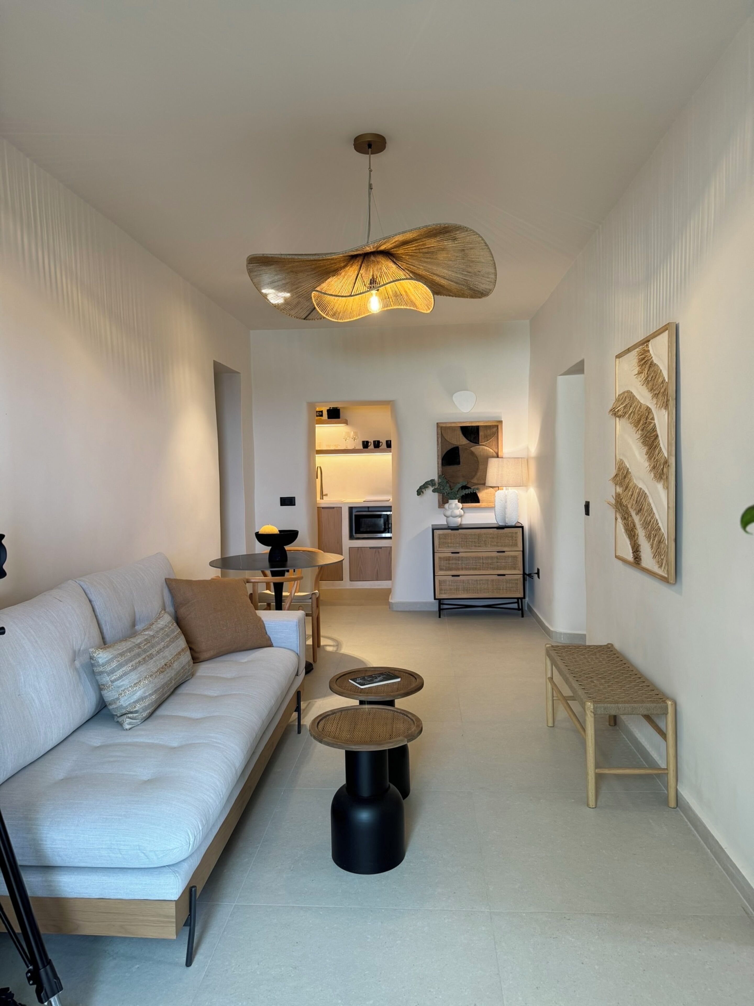 A modern living room with a sofa, coffee table, and a dining area with a table and chairs.