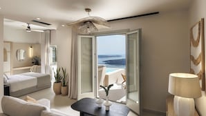 A modern hotel room with a balcony, a bed, a sofa, a table, and a lamp. - Morfes Luxury Suites by Caldera Houses (Santorini)
