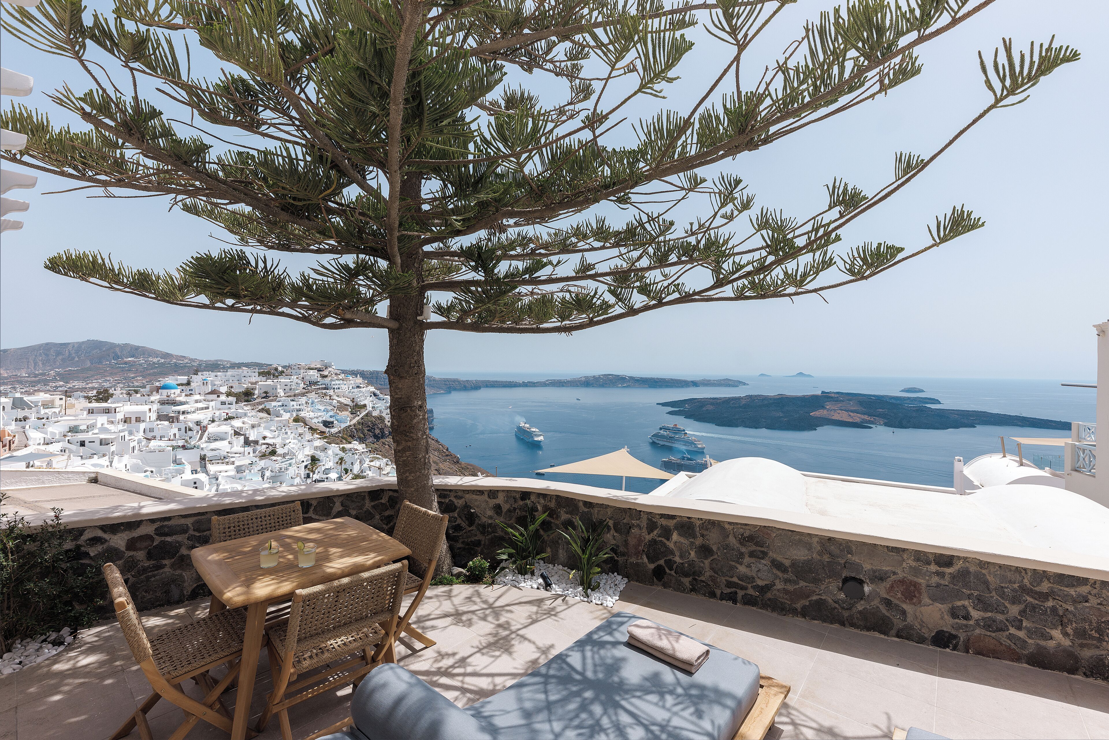Una terraza con mesa y sillas, con vistas a un pueblo costero y al mar.