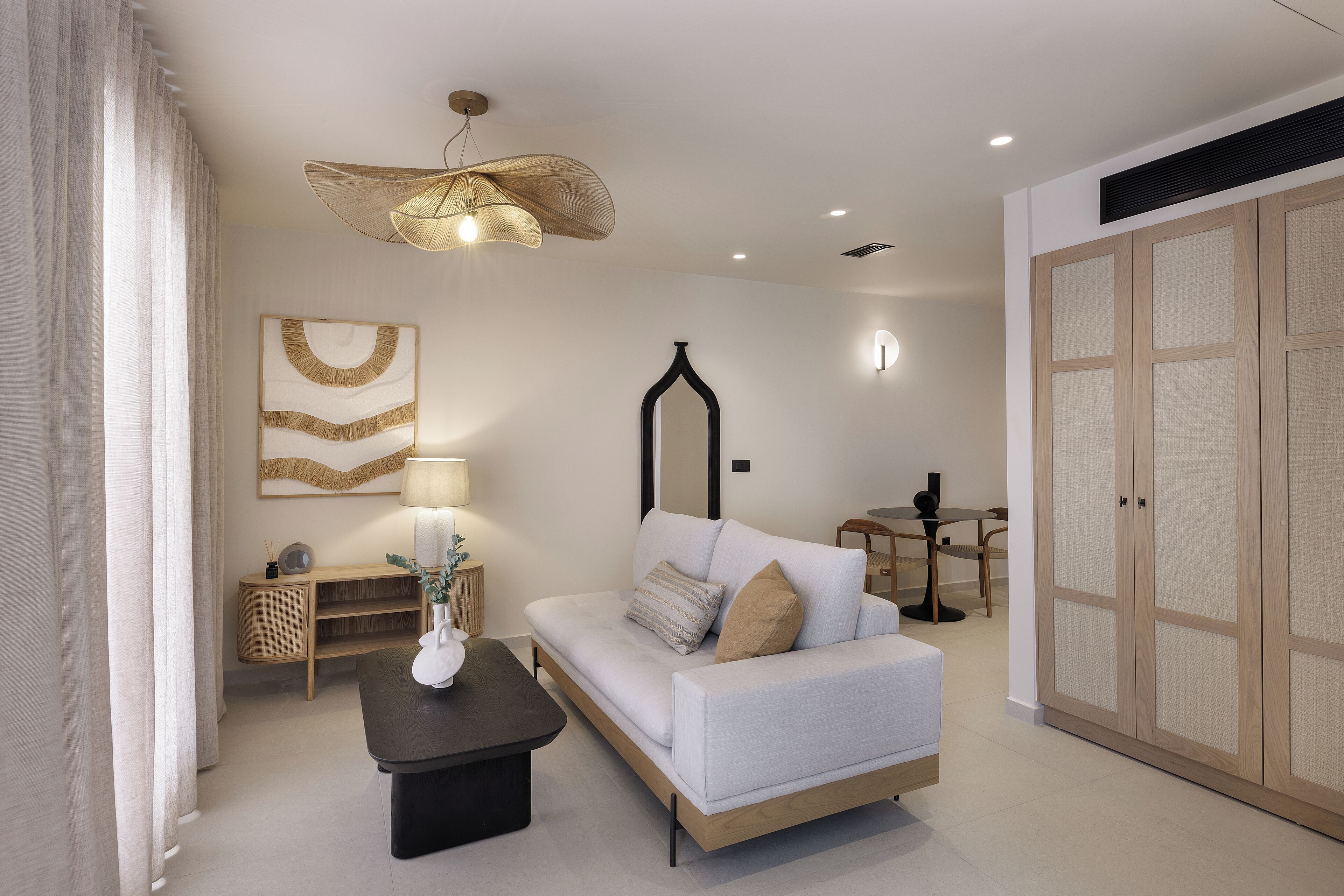 A modern living room with a sofa, a coffee table, a lamp, a side table, and a large wardrobe.