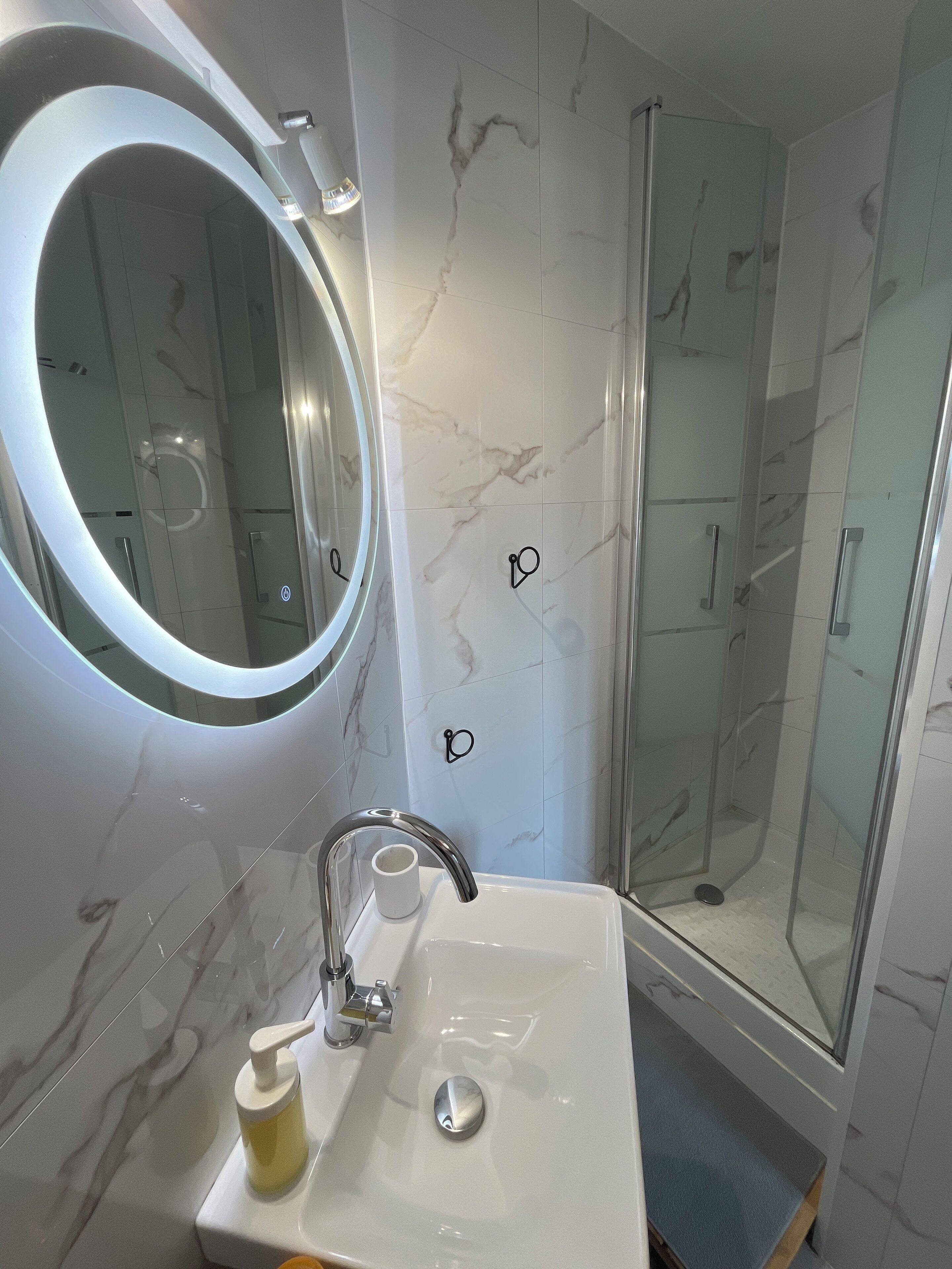 A bathroom with a modern sink, a round mirror, and a glass-enclosed shower.
