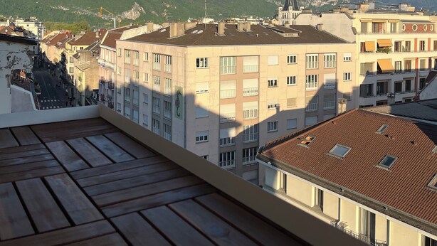 Un balcon offrant une vue sur la ville et les montagnes.