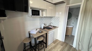 Une petite cuisine équipée avec un four à micro-ondes, un évier et des tabourets.