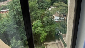 A view from a window overlooking a lush green landscape with dense foliage and scattered buildings. - Riverside Homes 6C (Nairobi)