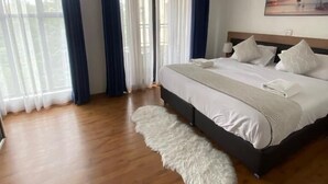 A bedroom with a large bed, a fluffy rug, and a painting on the wall. - Riverside Homes 6C (Nairobi)