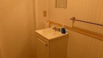 A small bathroom with a sink, mirror, towel rack, and toilet.
