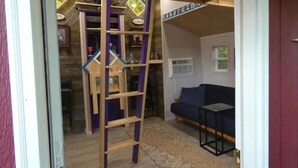 A room with a wooden ladder, a blue sofa, and a patterned rug. - The Tree House at Underhill Hollow (Thompson)