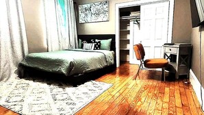 Un dormitorio con cama, escritorio, silla, armario y ventilador de techo.