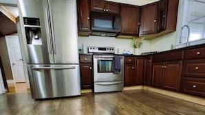 Una cocina con electrodomésticos de acero inoxidable, armarios de madera oscura y piso de madera.