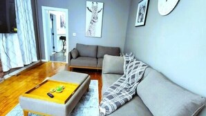 Una sala de estar con un sofá, una mesa de centro, un tapete y un reloj en la pared.