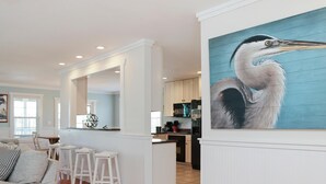 A modern kitchen with white cabinets, a black refrigerator, and a dining area with white stools. - Cape Dreamin' (Port St. Joe)