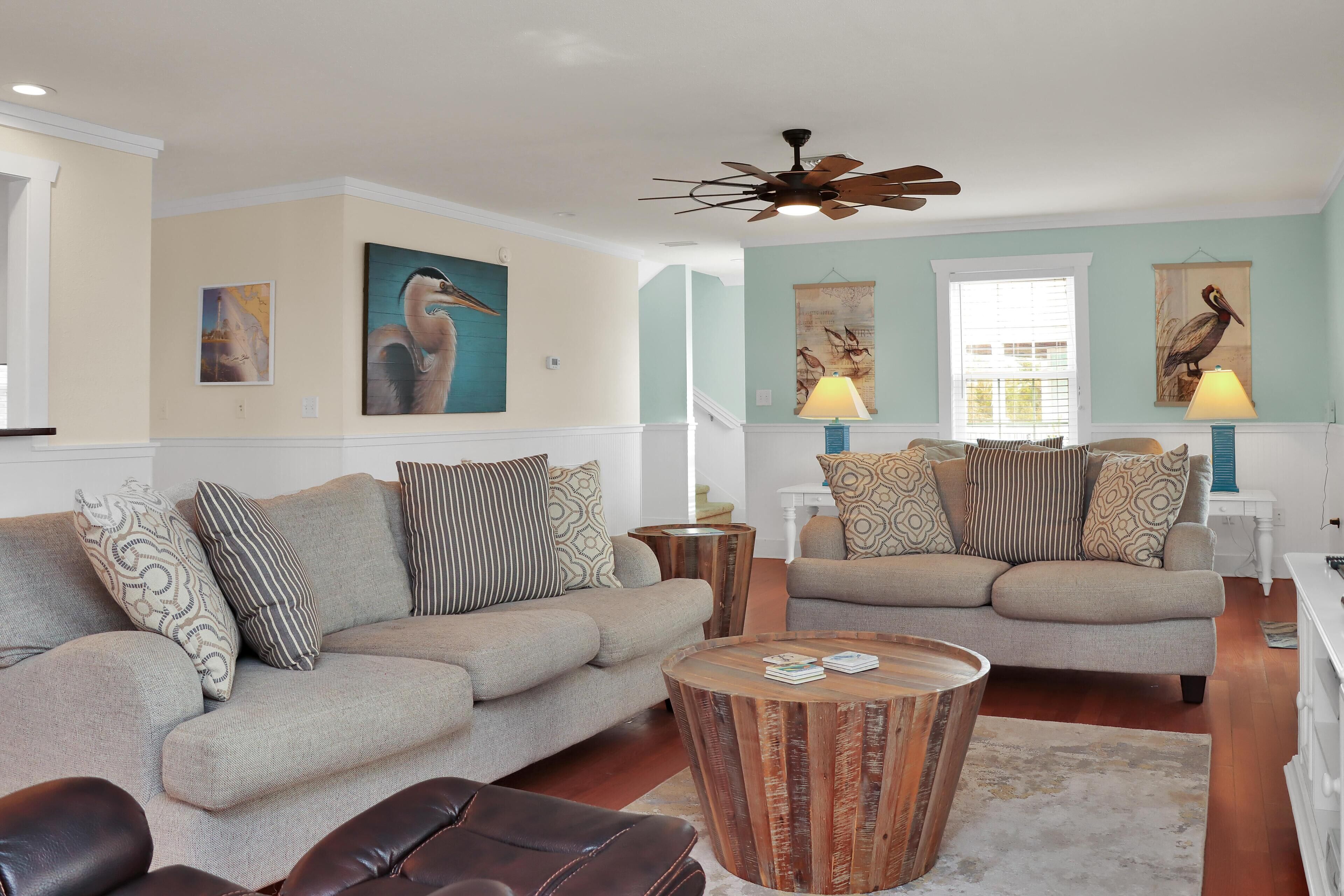 A living room with two sofas, a coffee table, and a ceiling fan.