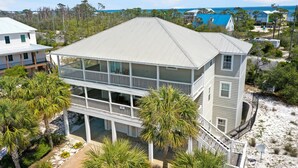 A two-story beachfront house with a balcony, surrounded by palm trees and a sandy beach. - Cape Dreamin' (Port St. Joe)