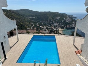 Ein rechteckiger Pool mit Blick auf eine Küstenstadt und Hügel.