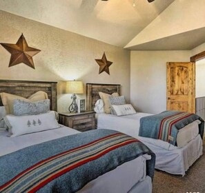 Une chambre avec deux lits, des décorations en forme d’étoiles sur le mur, une porte en bois et une table de chevet avec une lampe.