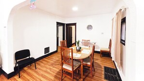 A dining area with a wooden table and chairs, a black bench, and a clock on the wall. - Best in Buffalo Entire First Floor up to 6 guests (Buffalo)