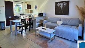 Un salon moderne avec un canapé gris, une table basse et un coin repas comprenant des chaises et une table.