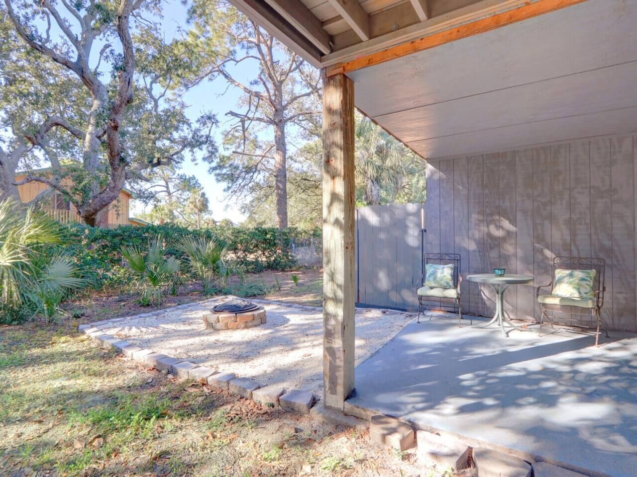 A covered patio area with a fire pit, outdoor seating, and a garden with various plants.