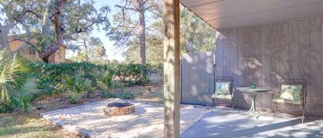 A covered patio area with a fire pit, outdoor seating, and a garden with various plants.