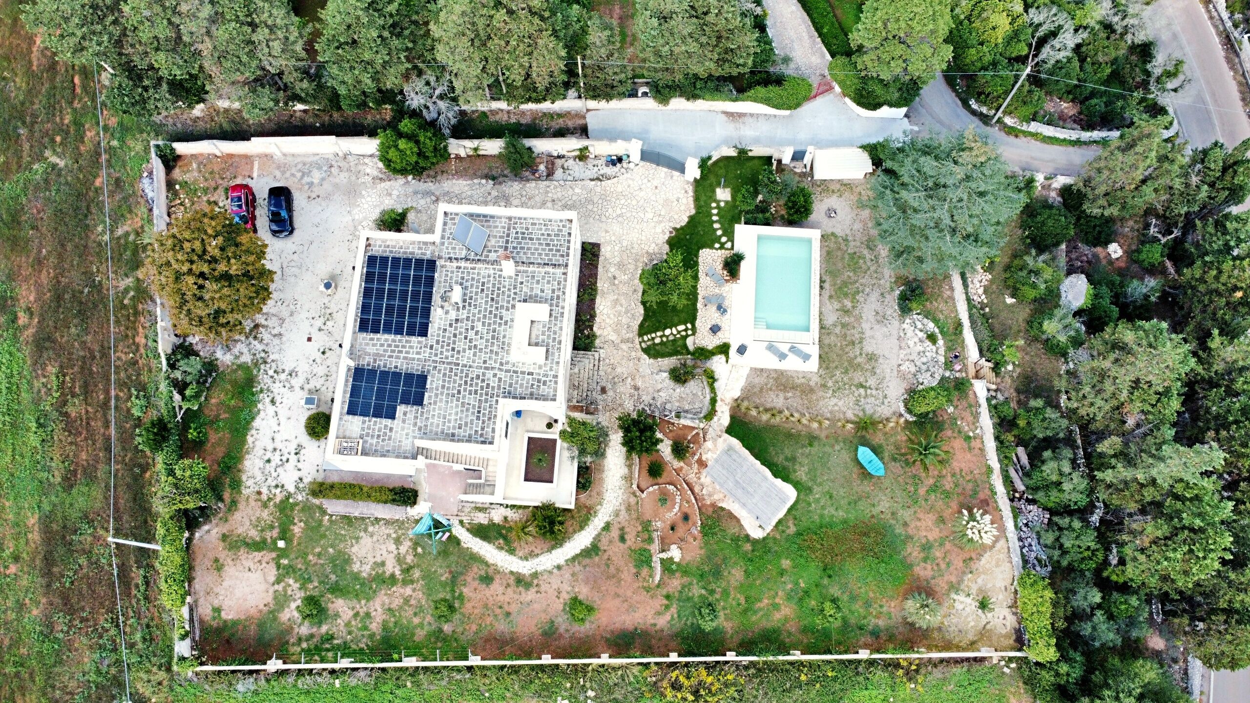 An aerial view of a property with a swimming pool, solar panels, and a fenced yard.