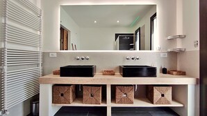 Ein modernes Badezimmer mit zwei schwarzen Waschbecken, einem großen Spiegel und Aufbewahrungsboxen unter der Ablagefläche.