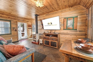 Un intérieur en bois avec une cheminée, un téléviseur fixé au mur et une table à manger avec des bols.