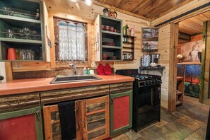 Une cuisine rustique avec des armoires en bois, un poêle et un évier.