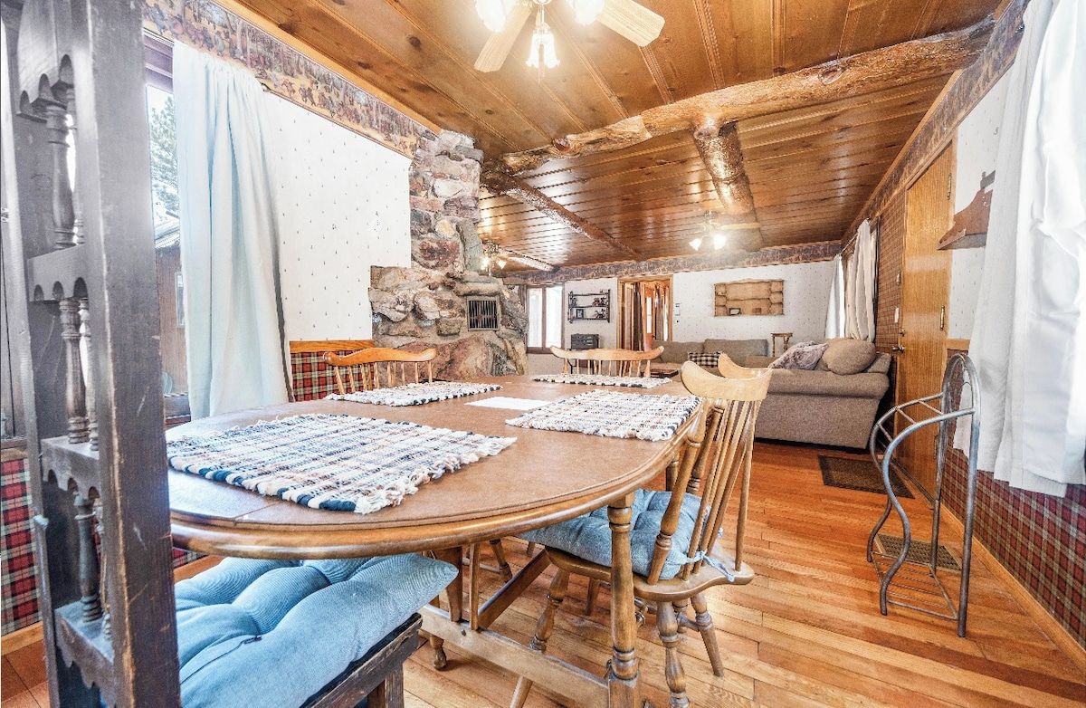 Un intérieur rustique avec un mur en pierre, un plafond en bois, une table ronde en bois avec des coussins bleus et un canapé.