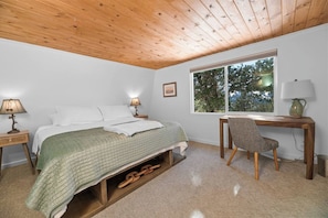 A bedroom with a bed, bedside lamps, a desk, and a chair.