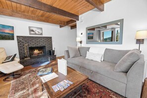 A living room with a fireplace, a sofa, a coffee table, and a chair. - Wondrous Juniper House (Big Bear Lake)